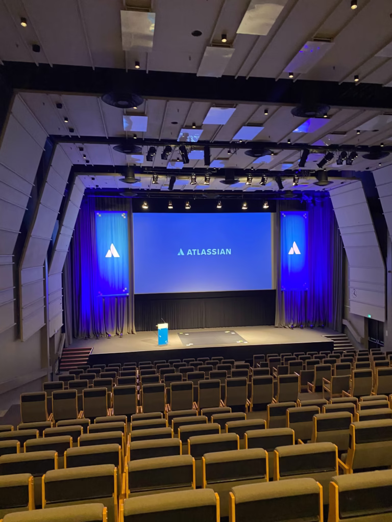 Atlassian keynote auditorium with branded stage screens and rows of seats